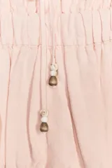 Top color rosa claro confeccionado con lino. Presenta escote recto con cordón ajustable con abalorios y tirantes finos. Detalle de acabados elásticos y frunces.