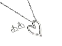 Set de joyería compuesto por un collar con dije de corazón y un par de aros tipo caravanas a juego, ambos con diseño de corazón entrelazado en acero.
