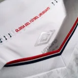 Camiseta de fútbol oficial Umbro del Club Nacional de Football, modelo Home 2026 de manga larga. Diseño en color blanco con cuello tipo polo, detalles en azul y rojo, y estampado de sponsors en el frente y mangas.