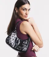 Bolso baguette Satinato de PU color negro, decorado con múltiples ojales metálicos plateados y remaches. Cuenta con un cierre de solapa frontal con hebilla metálica y correa para el hombro.