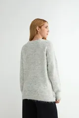 Buzo de punto con textura jaspeada, cuello redondo y mangas largas con puños acanalados.
