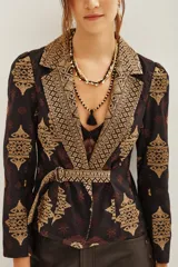 Saco de corte sastre con solapas anchas, confeccionado en algodón con estampado étnico en tonos oscuros y dorados. Presenta cierre frontal y diseño estructurado.