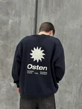 Buzo negro de corte holgado con cuello redondo y puños y bajo acanalados. Estampado frontal con un sol y la palabra "Osten" en blanco.