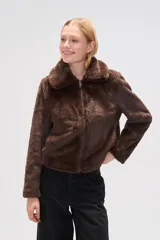 Chaqueta corta de piel sintética en color negro, con cuello clásico, cierre frontal con cremallera y mangas largas.