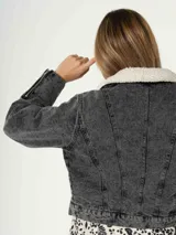 Campera de jean azul con cuello de piel sintética color crema, cierre frontal y cierres decorativos en los puños.