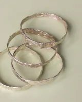 Esclava rígida de diseño artesanal con textura irregular y acabado metálico, ideal para uso diario.