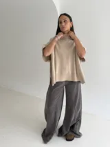 Poncho de tejido de punto color marrón chocolate, con cuello alto tipo polera y mangas cortas amplias. Presenta un diseño holgado con terminaciones acanaladas en el ruedo.