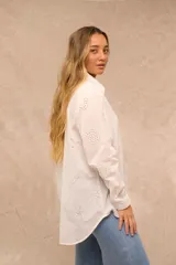 Camisa blanca oversize de manga larga, con cuello camisero, cierre frontal de botones y diseño bordado con motivos marinos perforados.