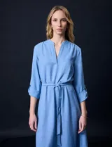 Vestido celeste de corte recto, con cuello en V, mangas 3/4 con presilla y lazo en la cintura.