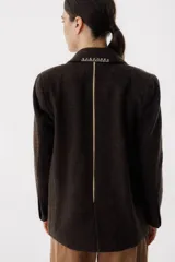 Blazer color verde oscuro con solapas con pespuntes blancos, de corte recto y cierre con un botón.