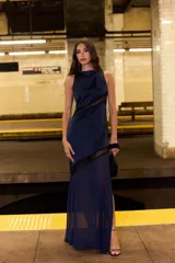Vestido largo azul marino sin mangas, con cuello alto drapeado y detalles diagonales de encaje negro semitransparente.