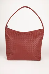 Bolso tipo shopper de símil cuero trenzado color marrón oscuro, con asas fijas centrales y gran compartimiento interior con tres bolsillos adicionales.