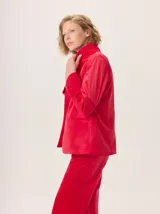 Blazer de mujer color rojo vibrante, confeccionado en material similar al terciopelo con un brillo sutil. Presenta solapas clásicas y forro interior estampado.