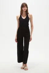 Pantalon jean negro de corte flare y tiro alto, con cierre frontal de botón y cremallera, y ruedo deshilachado.
