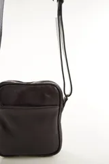 Morral bandolera de cuero genuino color marrón, con diseño compacto, cierre superior y correa ajustable para el hombro.