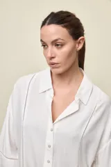 Camisa de calce relajado color celeste, con mangas 3/4, cuello clásico y cierre frontal con botones. Presenta detalles calados en el frente y en las mangas que aportan un acabado delicado al diseño.