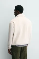 Sudadera de tejido polar con textura efecto pelo, corte relajado, cuello subido con cierre frontal de cremallera, manga larga con puños elásticos y bolsillo con cierre en el pecho.