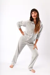 Conjunto de dos piezas confeccionado en tela plush, compuesto por una campera con cierre frontal y cuello alto, y un pantalón de corte recto. Presenta un diseño minimalista y cómodo en color gris claro.