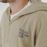 Canguro color marrón con capucha, cierre frontal parcial, bolsillo canguro y cordón ajustable en el dobladillo. Tiene un estampado blanco en el pecho con el texto "PULAU DESIGN DEPT." y un parche amarillo en la manga izquierda.