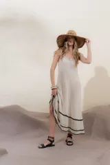 Vestido tejido de algodón y poliéster color crema, de corte largo y tirantes finos. Presenta un borde inferior con terminación artesanal en crochet con dibujo de calados en hilo negro.