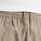 Pantalón cargo color beige, con cintura elástica ajustable con cordón, bolsillos laterales de doble entrada, dobladillo ajustable con broches y etiqueta tejida con el logo de New Balance.