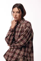 Camisa de manga larga con estampado de cuadros tartán en tonos marrones y beige, con cuello clásico y cierre frontal de botones.