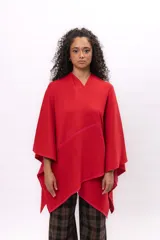 Ruana de tejido de punto color rojo, con diseño envolvente y bordes decorados con costuras a contraste en tono fucsia.