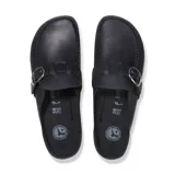 Zueco Birkenstock modelo Buckley, color negro, con diseño tipo mocasín, tira ajustable con hebilla metálica grande en el empeine, suela de corcho y base de goma negra con textura.