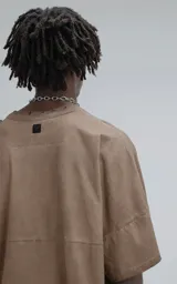 Remera de manga corta con calce extra oversize, color marrón chocolate con efecto gastado/deslavado. Presenta un corte con recortes horizontales en el frente y la espalda, y cuello redondo con terminación deshilachada.