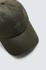 Gorra de algodón color verde oscuro, con efecto lavado y visera curva. Presenta un bordado discreto en el frente.