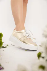 Championes urbanos dorados con cordones blancos y suela blanca con plataforma.