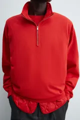 Sudadera de algodón ligero en color rojo, con cuello subido y cierre frontal de cremallera. Presenta mangas largas con puños acanalados y dobladillo inferior en rib.