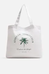 Bolso tipo shopper blanco de tela con asas de hombro. Estampado frontal con texto "Athletic Sports Club", una palmera y la frase "Embrace the lifestyle" con el año "Est. 1975".