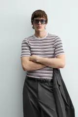 Camiseta de punto canalé slim fit, con cuello redondo y manga corta. Presenta un estampado de rayas horizontales en blanco, negro y rosado.