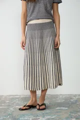 Pollera midi de punto con diseño a rayas verticales en colores crudo y azul navy, de corte acampanado y elástico en la cintura.