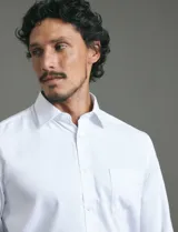 Camisa de vestir de manga larga en color azul claro, con cuello clásico, cierre frontal de botones y bolsillo en el pecho.