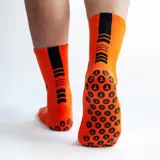 Medias deportivas de caña media color negro, con diseño técnico que incluye zonas de ventilación en el empeine y suela con puntos de silicona antideslizantes para mayor agarre. Presenta el logo de la marca bordado en el lateral.
