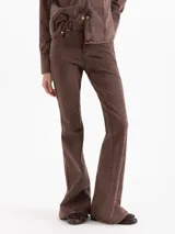 Pantalón de mezclilla marrón chocolate, de tiro medio y corte flare con perneras ligeramente acampanadas y costuras verticales decorativas en el frente.