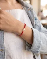 Pulsera elástica compuesta por cristales facetados en color rojo, intercalados con pequeñas cuentas de plata 925 y una perla central como detalle distintivo.