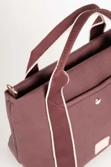 Cartera color beige con detalles en marrón claro, con doble asa corta y correa larga regulable y desmontable. Tiene un bolsillo externo y un compartimento interno con un bolsillo con cierre adicional.