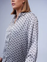 Camisa de satén estampado con diseño de cadenas en blanco y negro. Cuello con solapa, escote en V y abertura central con botones.