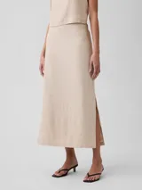Pollera midi de lino color beige, de corte recto y tiro alto, con abertura lateral en el dobladillo.