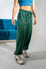 Pantalón de jogging verde oscuro con corte holgado, cintura elástica con cordón de ajuste y bolsillos laterales.