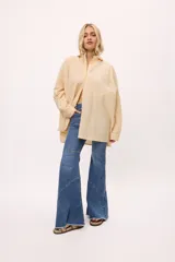 Camisa oversize de manga larga con diseño de rayas diagonales, cuello clásico y cierre frontal con botones. Presenta un corte holgado con recortes y doble cartera.