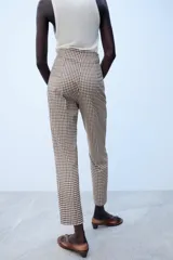 Pantalón de tiro alto con estampado de cuadros vichy en tonos marrón y blanco, con bolsillos laterales de vivo y corte recto.