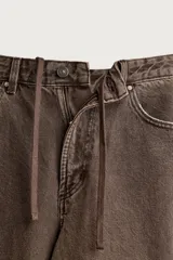 Pantalón barrel fit de mezclilla color verde militar, con efecto lavado, cinco bolsillos, cierre frontal con cremallera y botón, y detalle de pinzas en las rodillas.