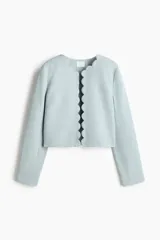 Chaqueta celeste de manga larga, con cuello redondo y frente abierto con bordes festoneados.