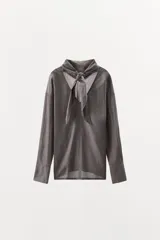 Camisa de algodón con diseño a rayas verticales, escote en pico con detalle de pañuelo ajustable mediante lazada, manga larga con puños abotonados y aberturas laterales en el bajo.