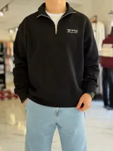 Buzo negro con medio cierre frontal, cuello alto y bordado con la inscripción "Top Style" en el pecho.
