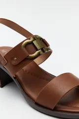 Sandalias de cuero color marrón con tacón cuadrado y hebilla lateral.